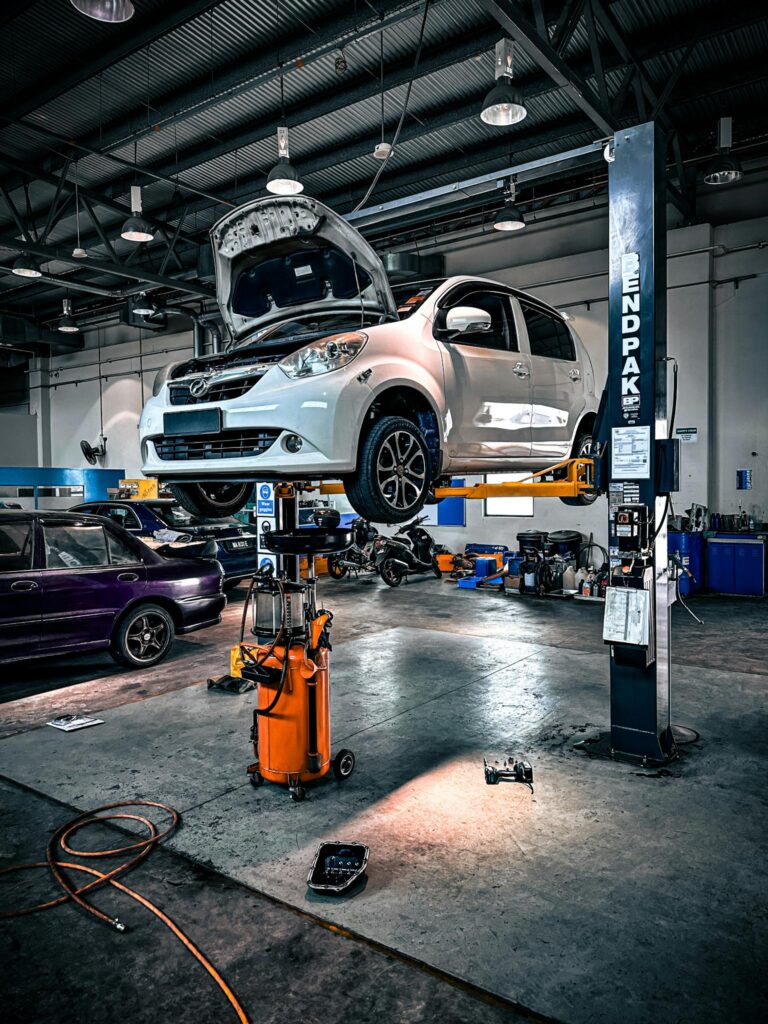 A car is lifted on a hydraulic lift in a well-equipped auto repair shop.